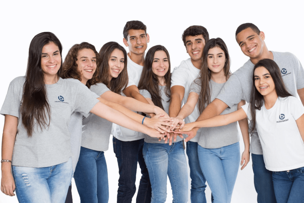 Grupo de alunos do Colégio Bahiense em meio círculo com as mãos unidas sorrindo para a câmera