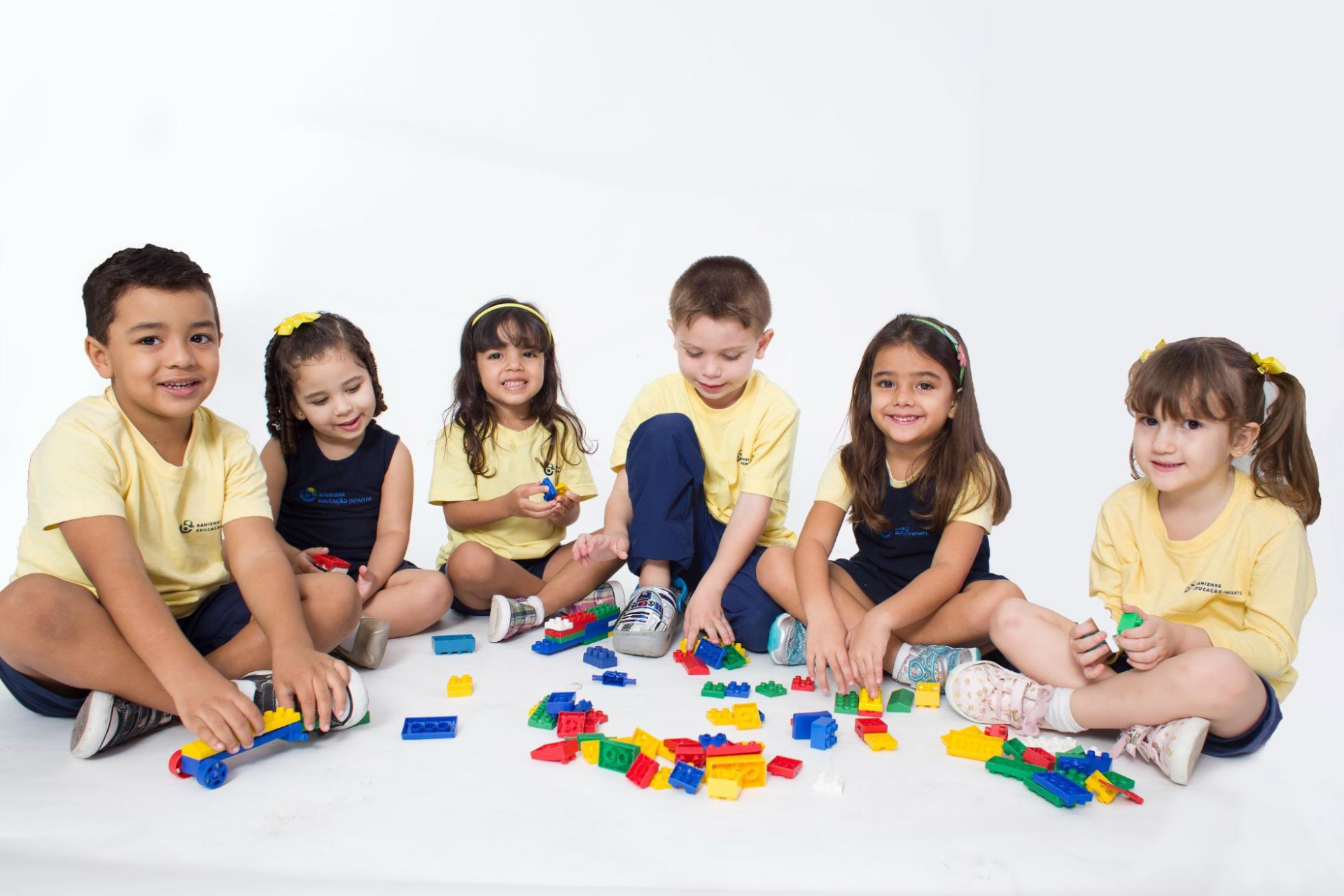 Grupo de alunos sentados em meio círculo e brincando com Lego