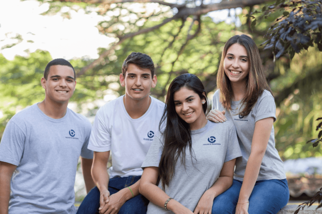 Grupo com 4 estudantes uniformizados do ensino médio em foco ao ar livre