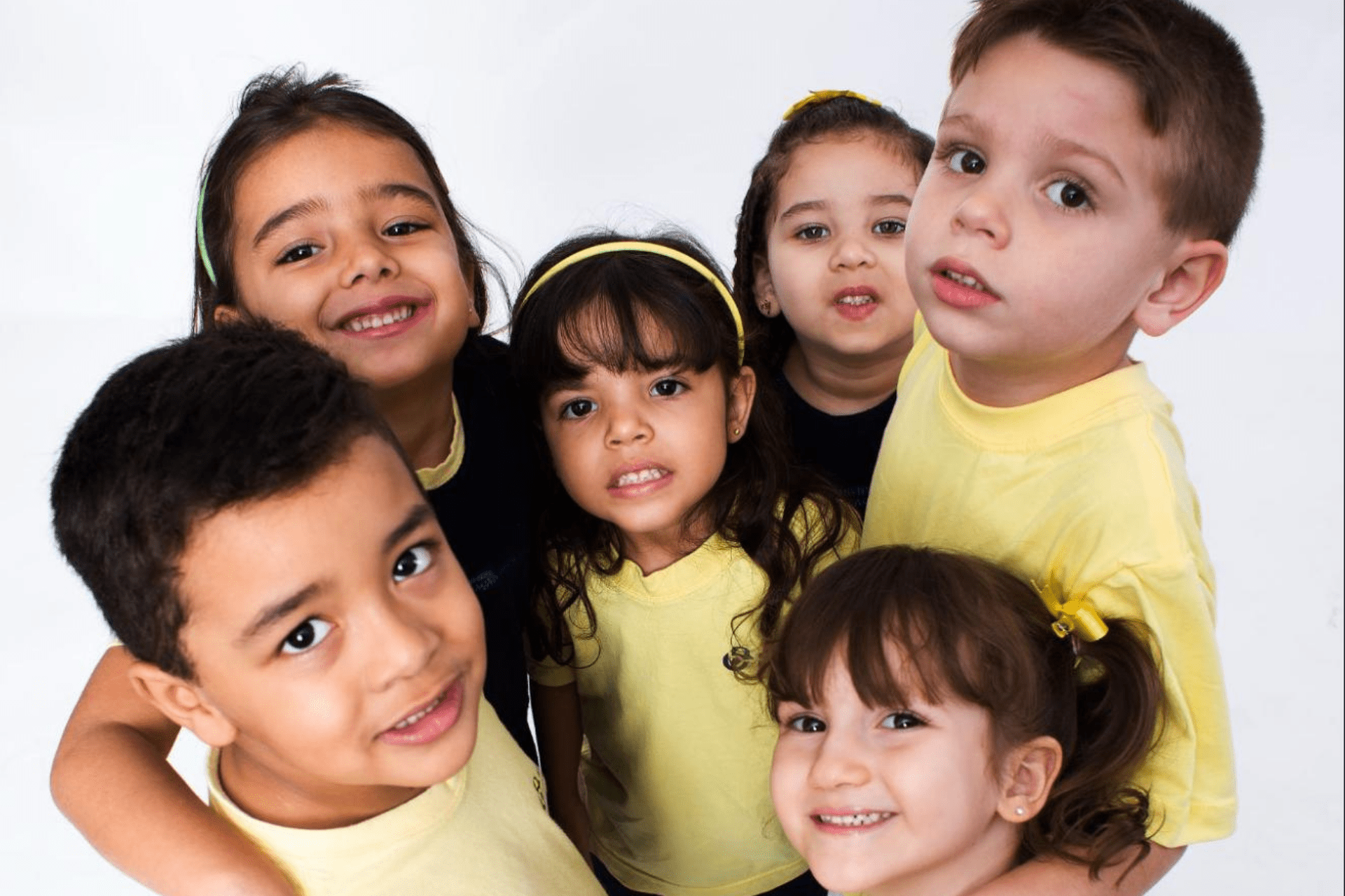 Cinco alunos do ensino infantil com inteligência emocional abraçados em um círculo