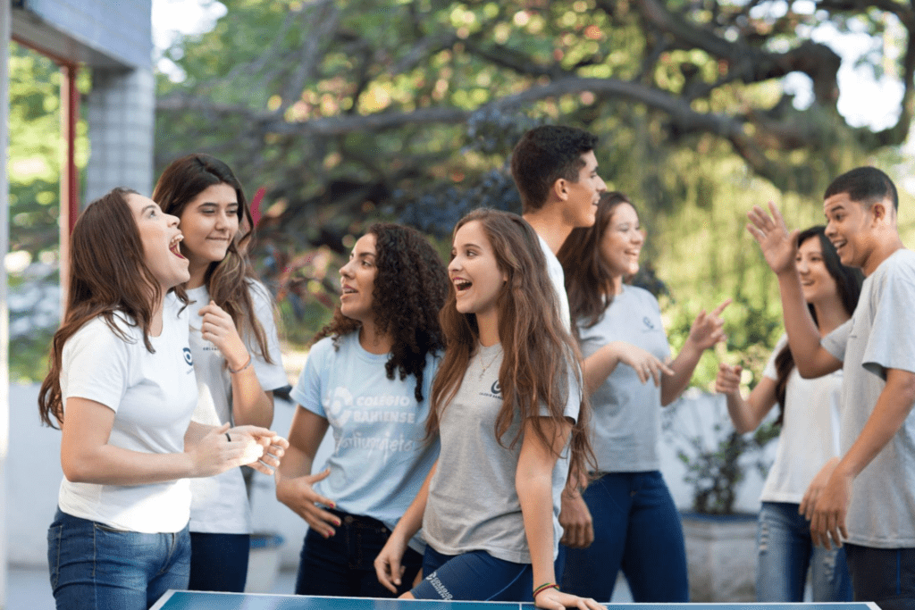 Alunos descontraídos e sorrindo entre si em um intervalo de aula prestes a entrar para o novo Ensino Médio