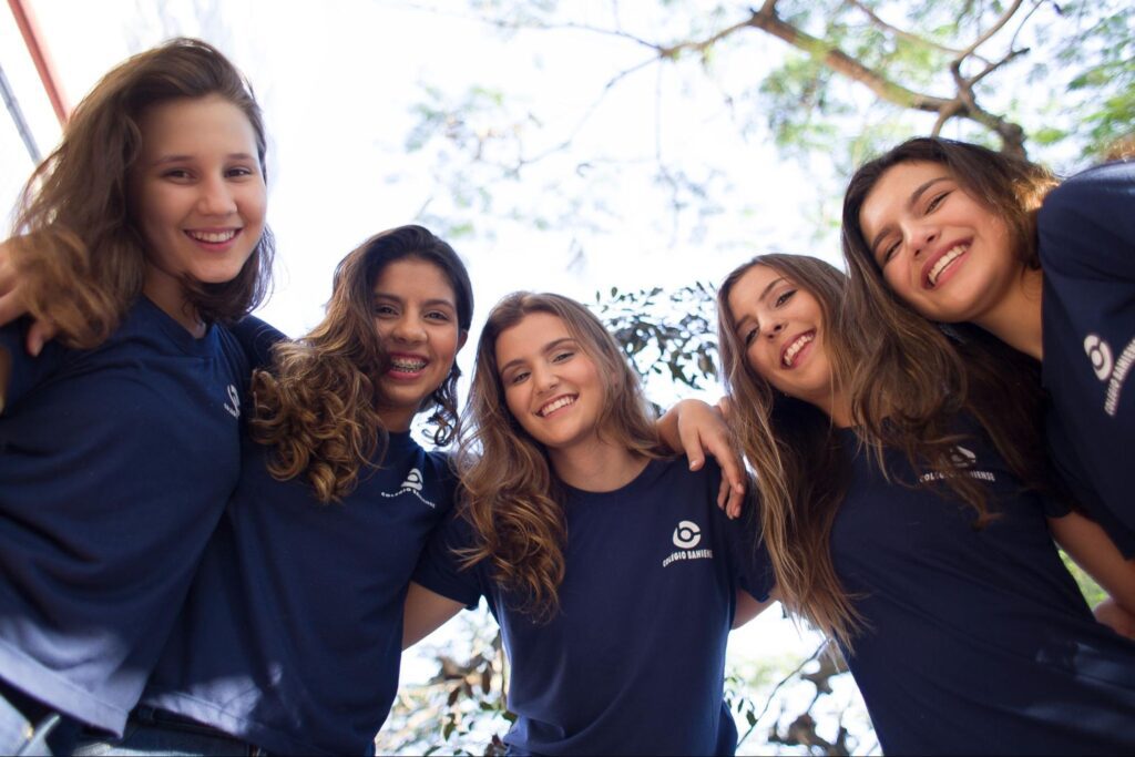 Alunas do Colégio Bahiense se abraçando e sorrindo para a câmera