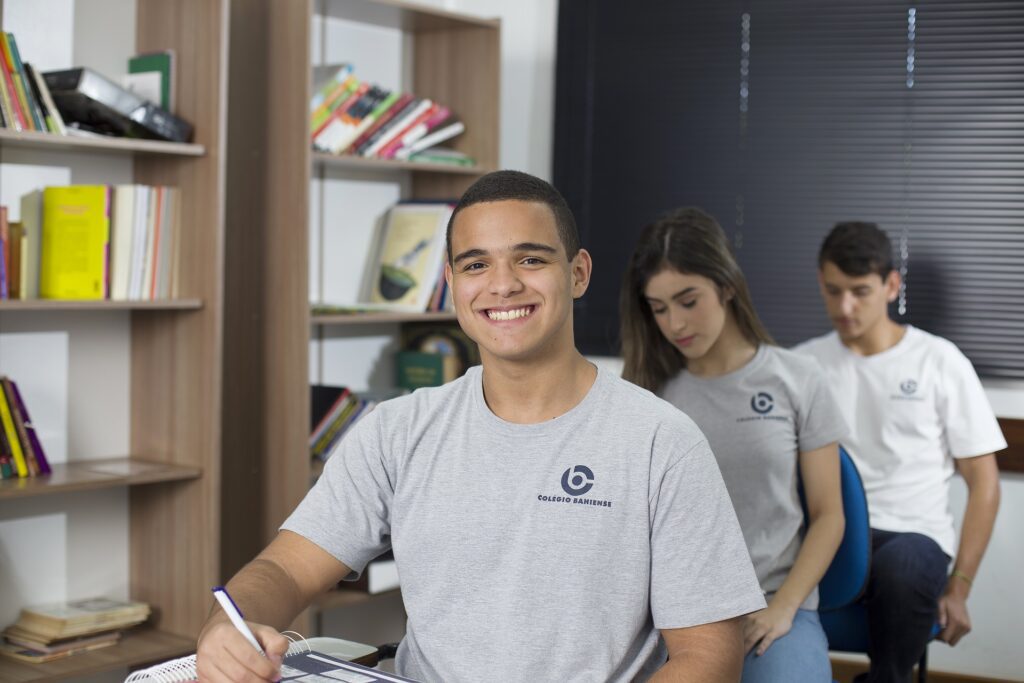 Aluno Ensino Médio em sala sorrindo para câmera