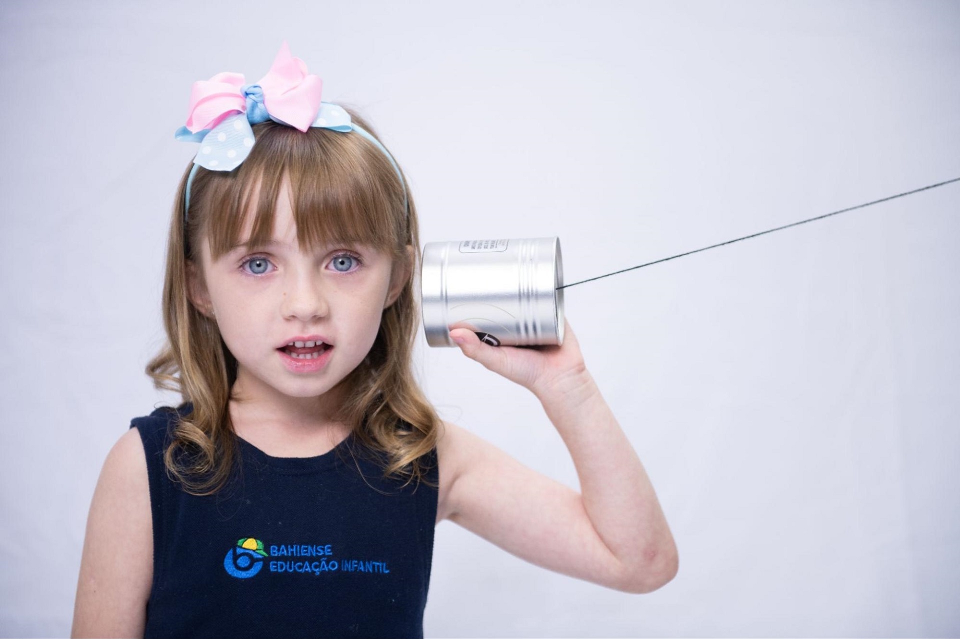 menina brincando com telefone de lata e estimulando o desenvolvimento infantil