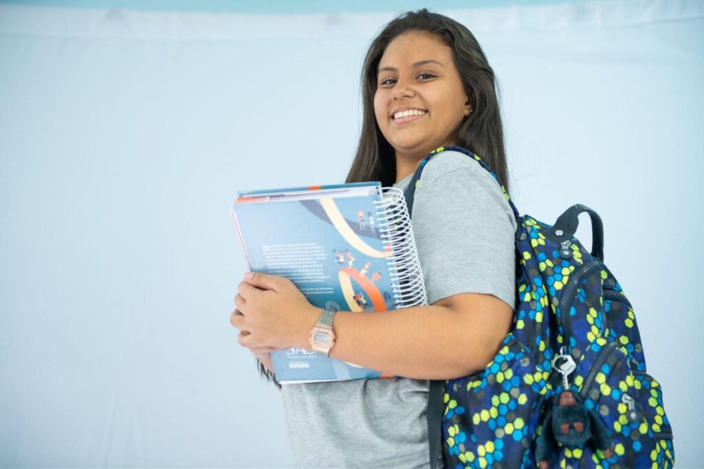 menina feliz na escola de Ensino Médiocom livros e mochila