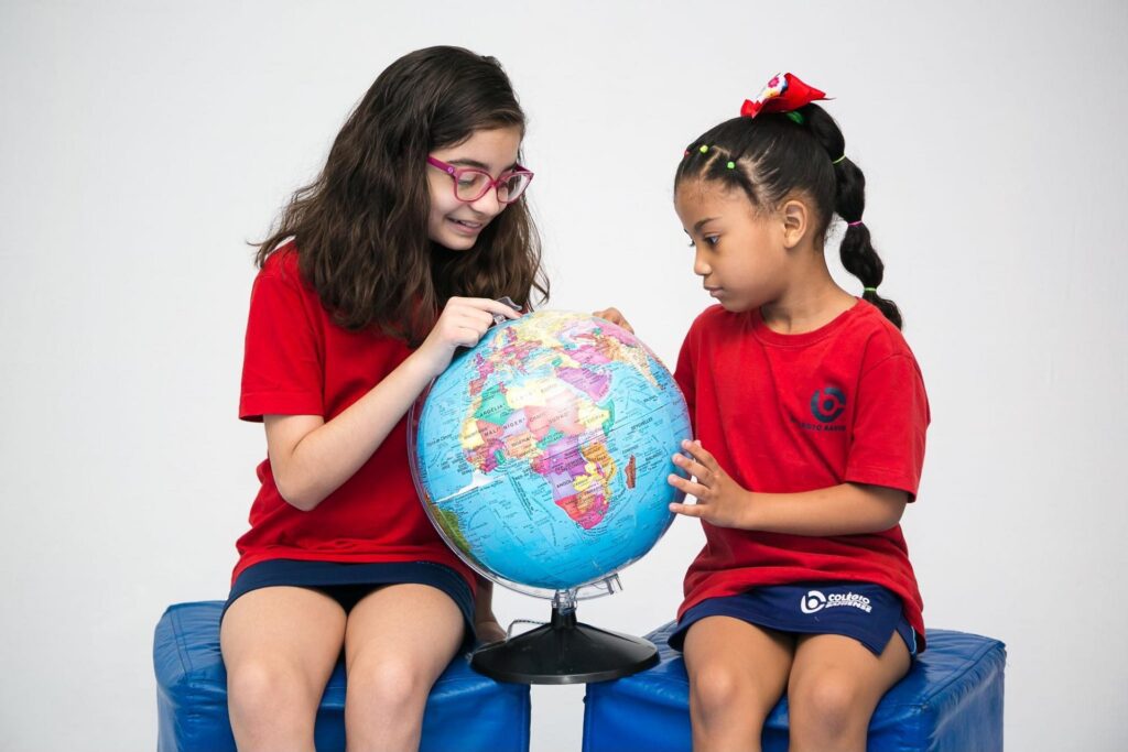 crianças estudando inglês em casa e apontando pro globo terrestre