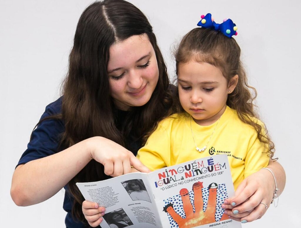 Criança lendo livro com irmã mais velha