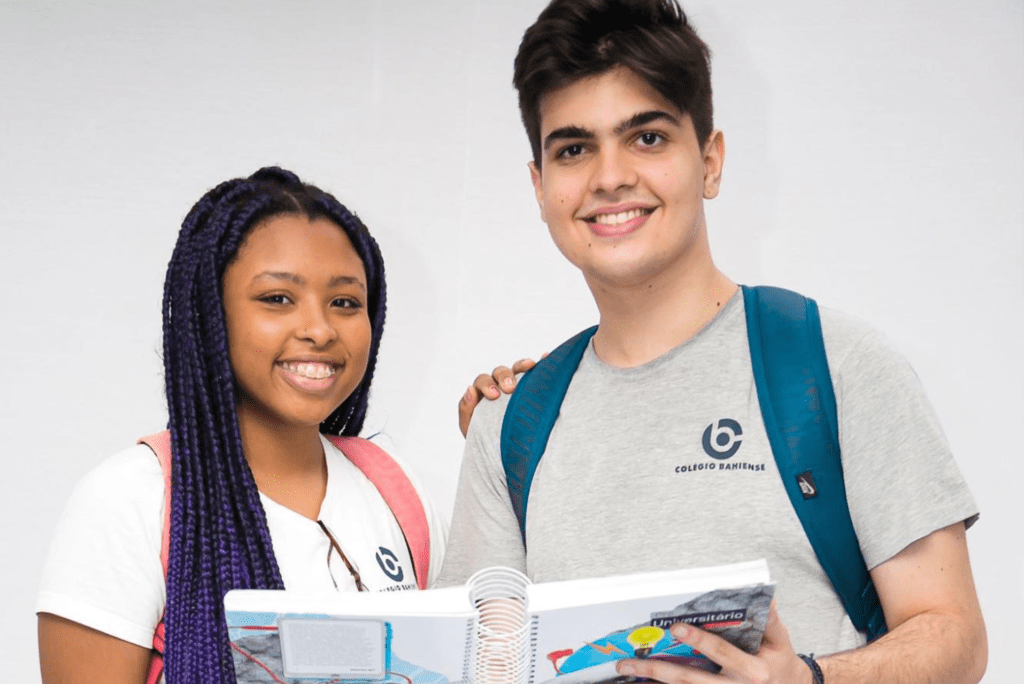 Dois jovens do Colégio Bahiense posando para foto enquanto seguram um caderno de anotações sobre rotina de estudo