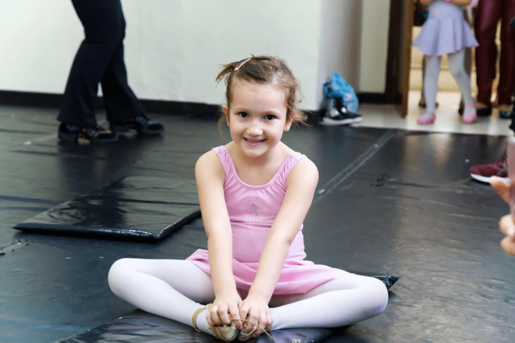 Criança sentada ao chão vestida de roupa de ballet