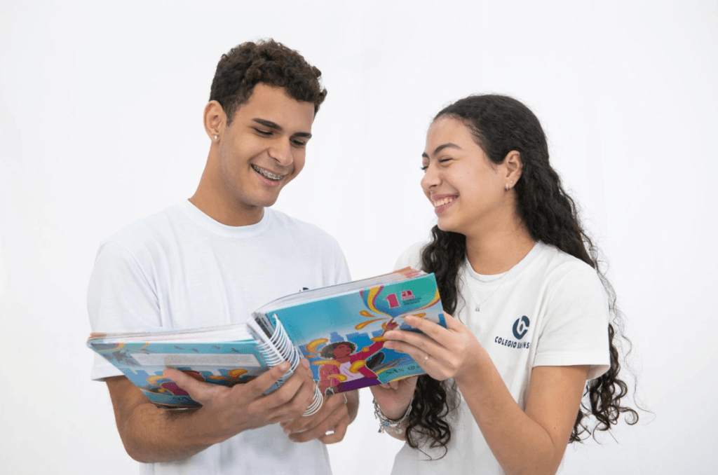 Dois alunos adolescentes do Colégio Bahiense posando para foto segurando caderno